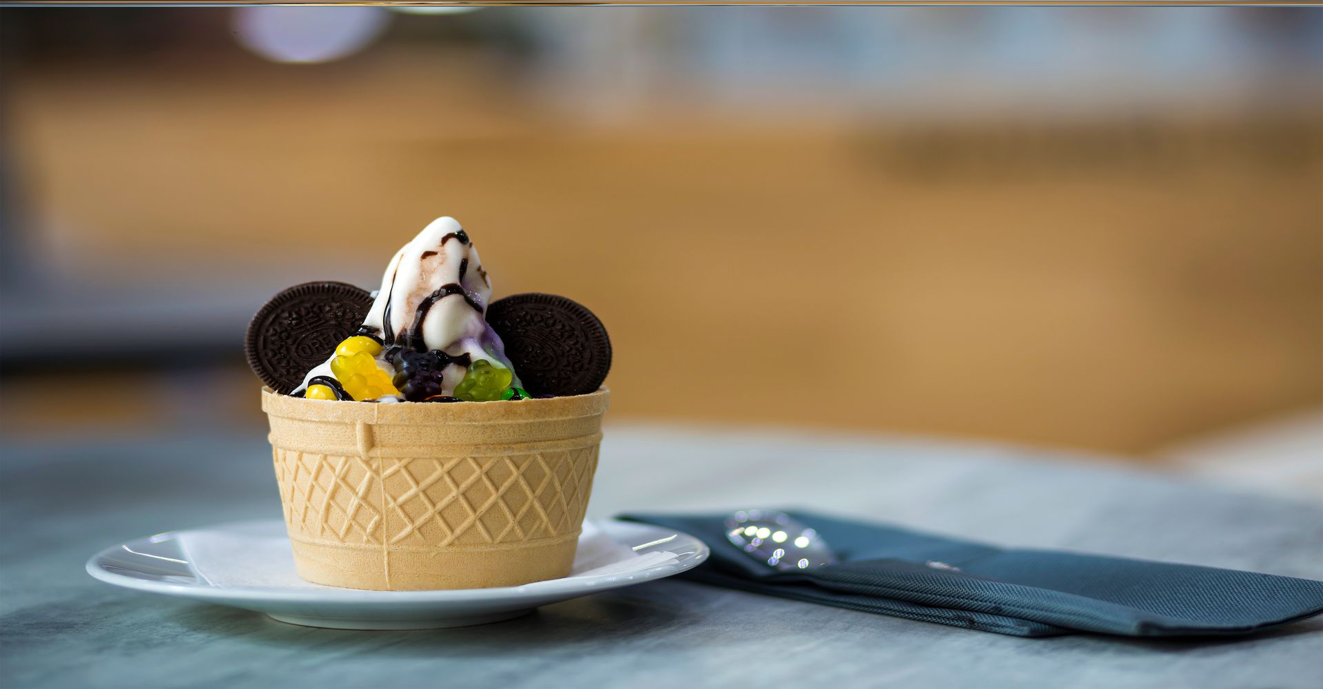 white-plate-with-ice-cream-dessert-wafer-cup-with-chocolate-cookies-creative-decoration-topping-blurred-colorful-interior